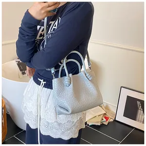 Detail of light blue woven bucket bag with knot handle and detachable shoulder strap