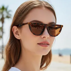Cat eye tortoiseshell sunglasses with brown lenses worn by model on a sunny beach