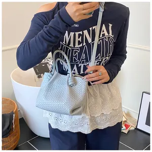 Detail of light blue woven leather bucket bag with top handle knot and shoulder strap