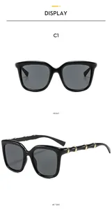 Detail of black square sunglasses featuring gold metal rings on bamboo-style temples
