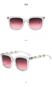Detail view of pink gradient lenses and golden bamboo-shaped metal temple on sunglasses