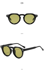 Détail de lunettes de soleil rondes rétro à monture noire, verres jaunes et rivets