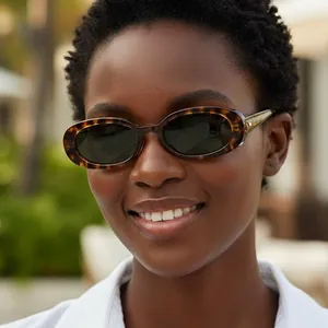 Vintage oval tortoiseshell sunglasses with dark lenses worn by a model in outdoor setting