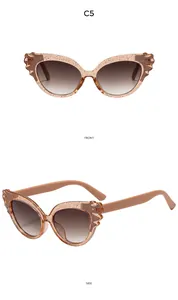 Detail view of pink glitter cat-eye kids sunglasses with winged frames and brown gradient lenses