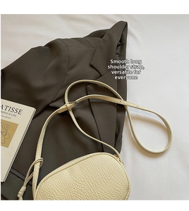 Detail of creamy white litchi textured leather crossbody bag with adjustable long strap