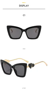 Detail of cat eye sunglasses with gold temples and layered black heart accents on frame