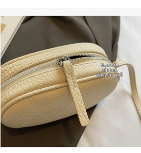 Detail of smooth silver zipper and pebbled leather texture on beige pillow bag