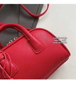 Close-up of red litchi texture leather shoulder bag with silver metal zipper detail