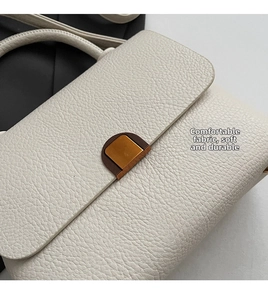 Gros plan du sac à main en cuir grainé blanc cassé avec fermoir doré semi-circulaire