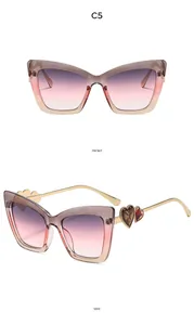 Detailed view of cat eye sunglasses with heart-shaped metal accents and gradient lenses