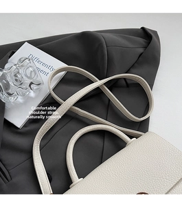 Détail du sac à bandoulière blanc à texture litchi avec poignée ronde et sangle réglable