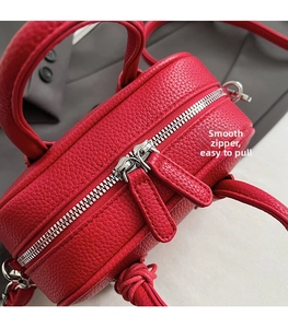 Detail of smooth silver double zipper and red lychee grain leather texture on the shoulder bag