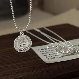 S925 sterling silver queen coin necklace with embossed portrait on a vintage wood surface