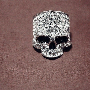 Gothic punk style skull ring with full rhinestone inlay on brown textured surface