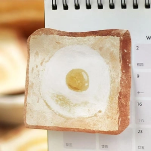Detailed shot of creative toast-shaped sticky note with fried egg pattern on a calendar