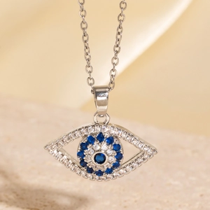 Vue macro du pendentif œil maléfique avec cristaux bleus sur pierre beige et satin