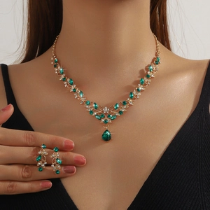 Close-up of bridal jewelry set with emerald gemstones and gold-plated leaf necklace