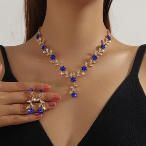Elegant gold bridal jewelry set with deep blue crystals and floral leaf necklace