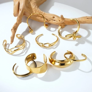 Minimalist gold-plated open bangles with hollow texture and polished finish on wood