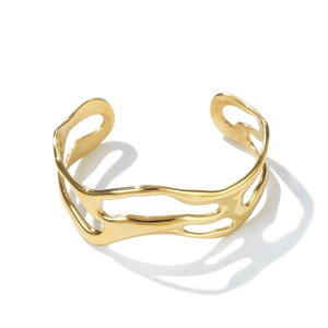 Detail of gold hollowed liquid metal texture open bangle with high polish mirror finish