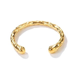 Detail of minimalist gold open bangle featuring artistic hammered texture and polished finish