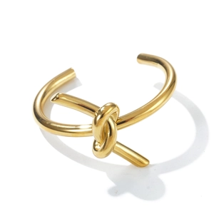 Detail of a minimalist gold-plated knot bangle with a sleek open-end design for women