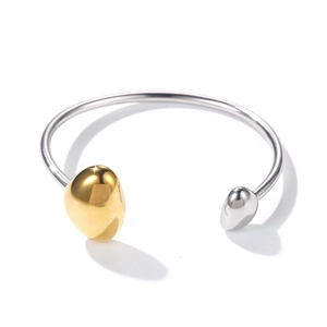 Macro detail of open stainless steel cuff bracelet with asymmetrical gold bean accents