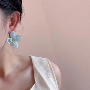 Boucles d'oreilles fleurs en acrylique bleu clair portées par un mannequin chic