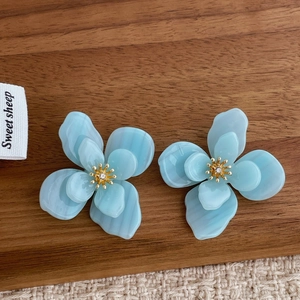 Gros plan de boucles d'oreilles fleurs en acrylique bleu avec cœur doré et strass