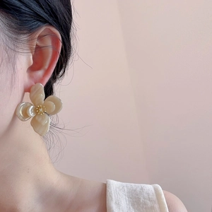 Gros plan de boucles d'oreilles fleurs en acrylique double couche sur un modèle