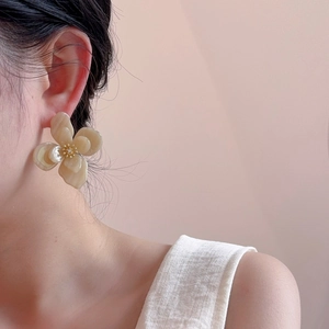 Détail de la boucle d'oreille fleur en acrylique beige avec centre doré sur modèle