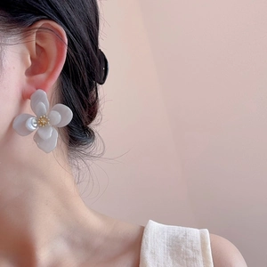 Gros plan de boucles d'oreilles fleurs en acrylique double couche avec perle dorée