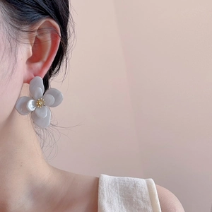 Gros plan de boucles d'oreilles fleurs en acrylique translucide avec perle dorée