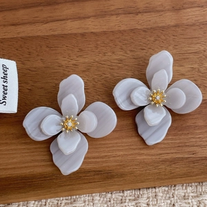 Détail de boucles d'oreilles fleurs en acrylique double couche et zircon doré