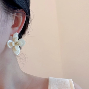 Gros plan de boucles d'oreilles fleurs en acrylique double couche blanc crème sur mannequin