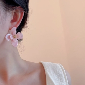 Gros plan de boucles d'oreilles fleurs en acrylique rose portées par un mannequin
