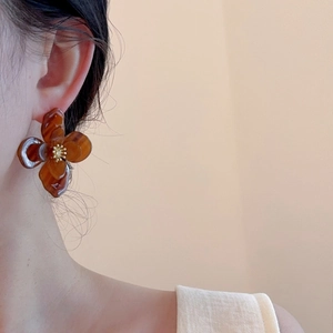 Détail de la boucle d'oreille fleur en acrylique ambre avec étamines dorées sur un modèle