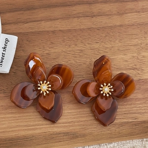 Vue détaillée des boucles d'oreilles fleurs en acrylique ambre avec étamines dorées
