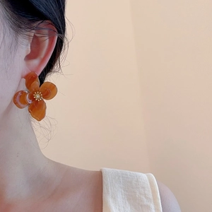 Gros plan sur d'élégantes boucles d'oreilles fleurs en résine ambre et centre doré