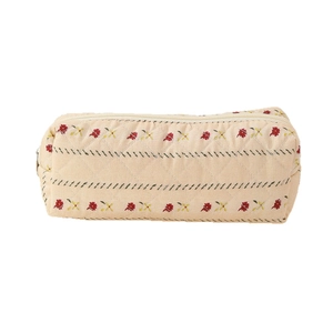 Quilted cotton makeup pouch with floral embroidery and zip closure on white background