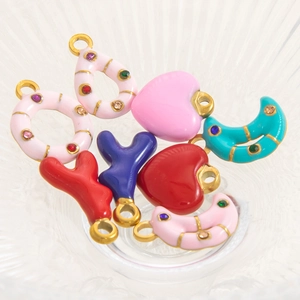 Macro shot of colorful enamel moon and heart pendants with rhinestones for DIY jewelry