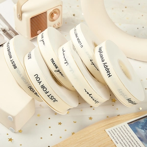 Detail of cream grosgrain ribbons with black English text for gift box wrapping