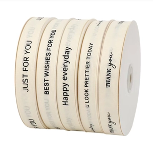 Detail of five rolls of off-white cream ribbons with black English greeting typography