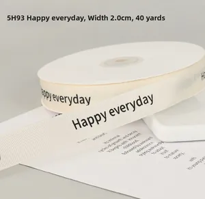 Close-up of 2cm off-white grosgrain ribbon with Happy Everyday print for gift wrapping