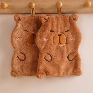 Detail of two brown cartoon capybara hand towels in coral fleece hanging on wooden hooks