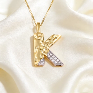 Close-up of letter K pendant featuring hammered gold texture and pavé zircon stones