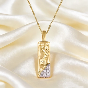 Detail of vintage gold rectangular pendant with embossed figure and zircon inlay