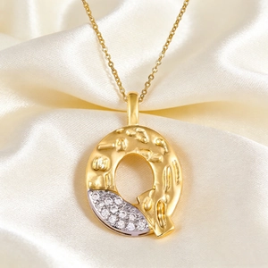Macro detail of letter Q pendant with hammered gold texture and micro-pave zircons