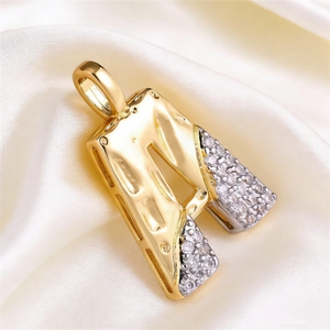 Macro detail of gold-plated letter A pendant with micro-pave cubic zirconia inlay