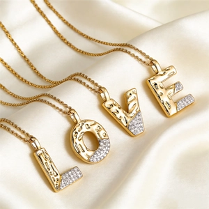 L-O-V-E letter necklaces with hammered gold finish and zircons on white silk fabric